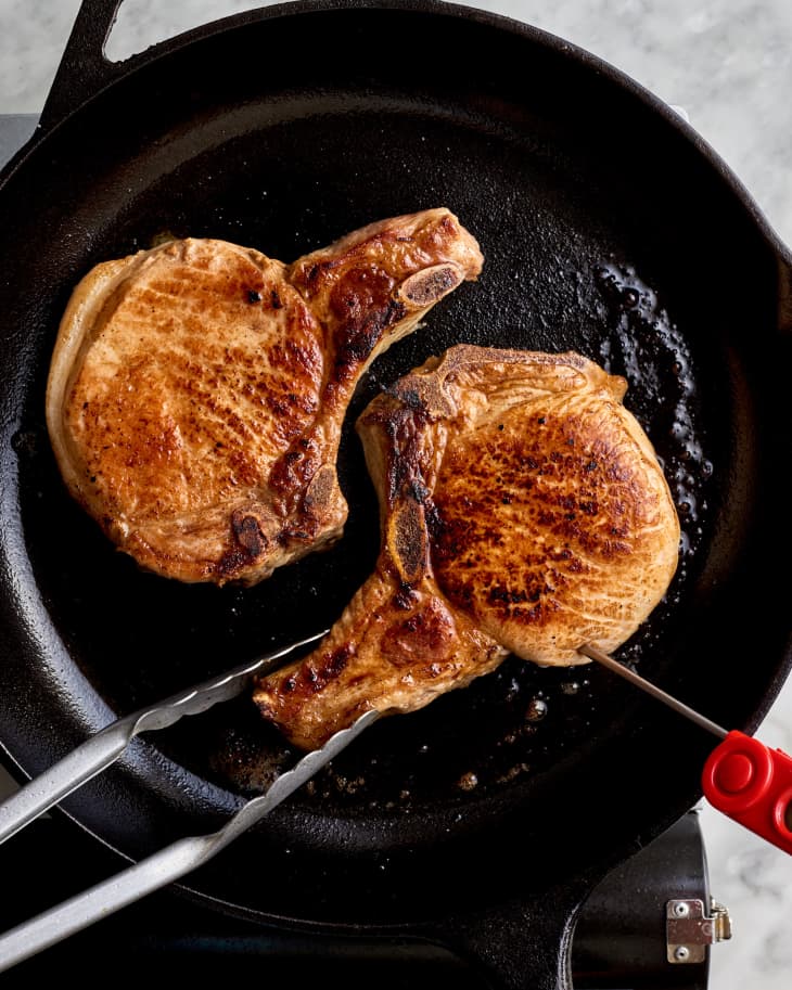 pork chops in a skillet, searing, having their temperature taken properly