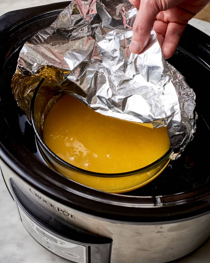 lemon curd being made in a bowl inside a slow cooker
