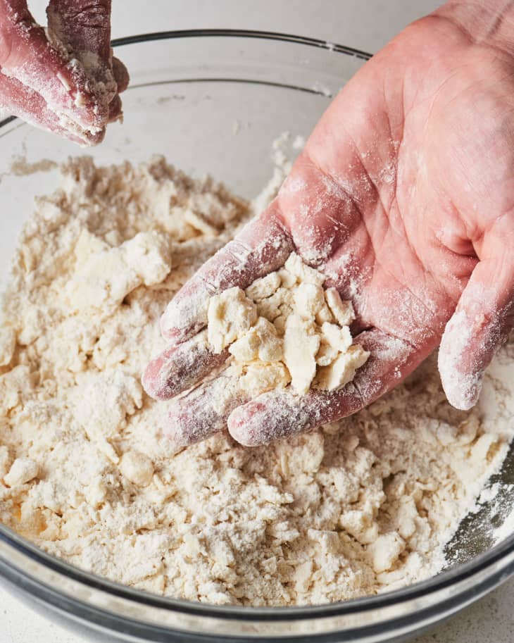 hands mixing grated butter into dry ingredients, showing texture