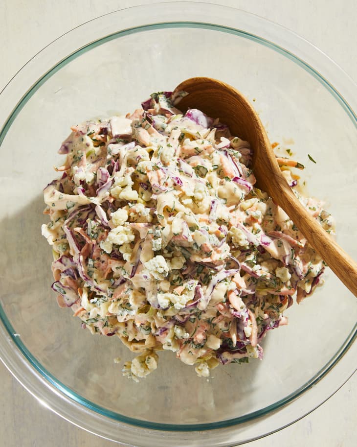 Ina Garten coleslaw in a bowl with wooden spoon.