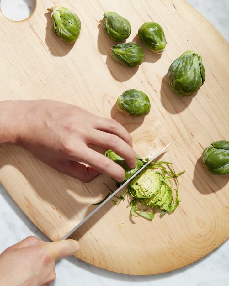 brussels sprouts being chopped on cutting board