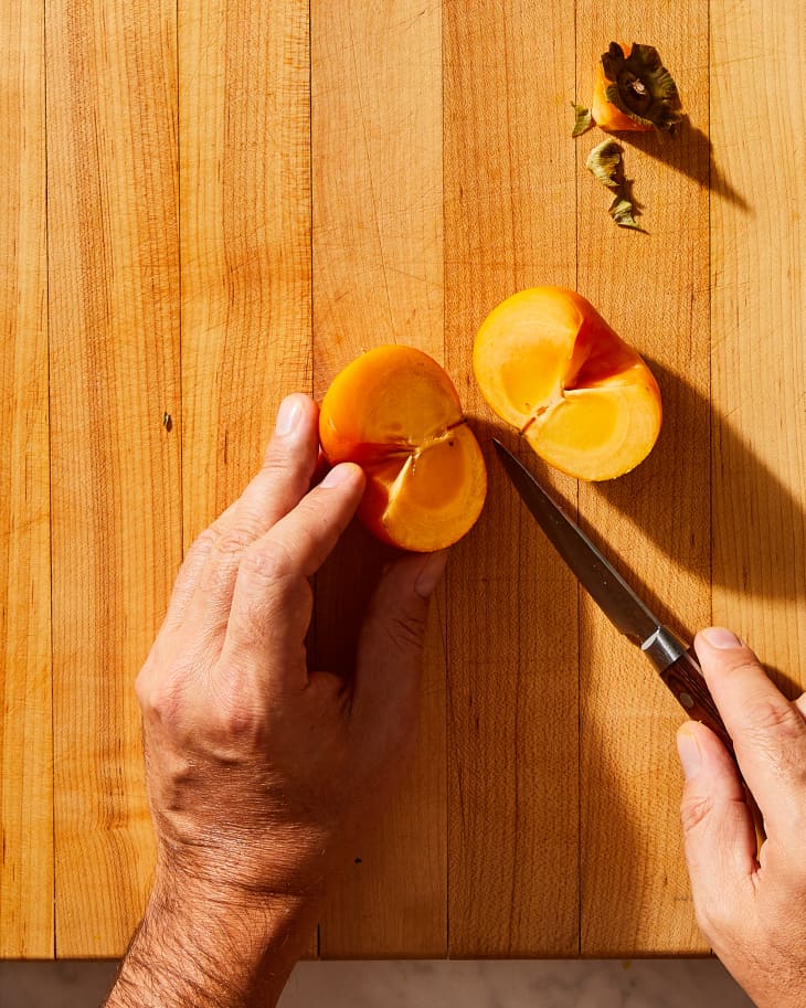 someone cutting a persimmon in half