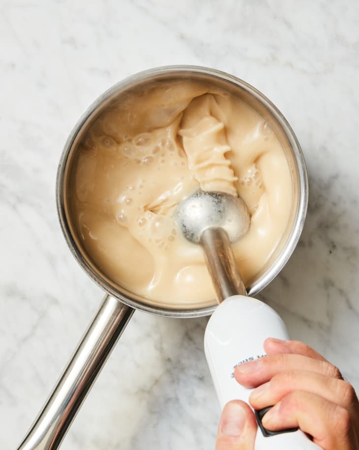 Someone trying to smooth out lumpy gravy with an immersion blender