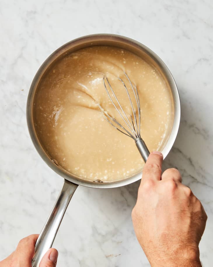 Someone trying to smooth out lumpy gravy with a whisk