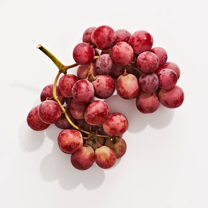 Red globe grapes on a white surface.