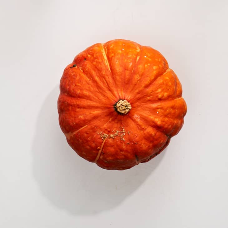 Red Kabocha squash on a white surface.