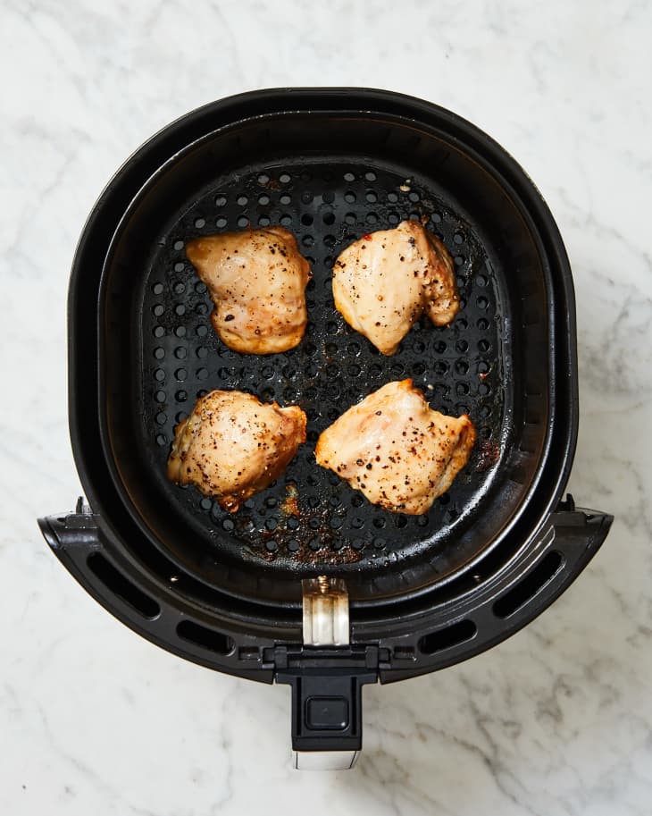 Overhead photo of boneless skinless chicken thighs cooking in air fryer
