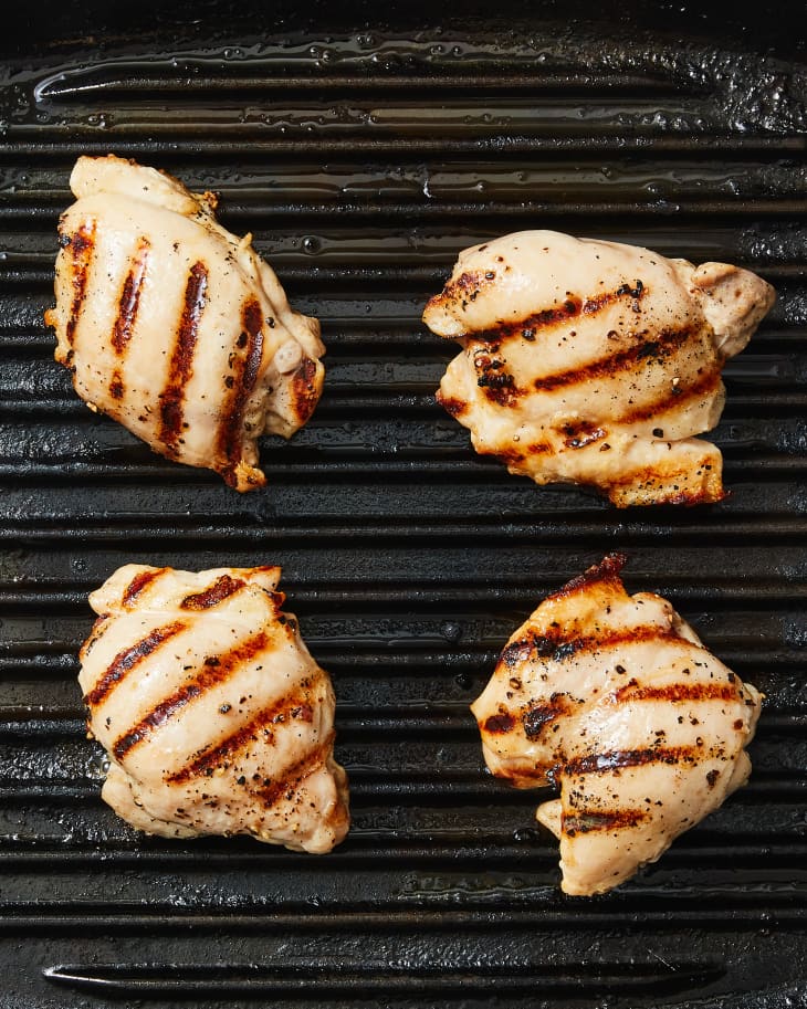 Overhead photo of boneless skinless chicken thighs cooking on grill