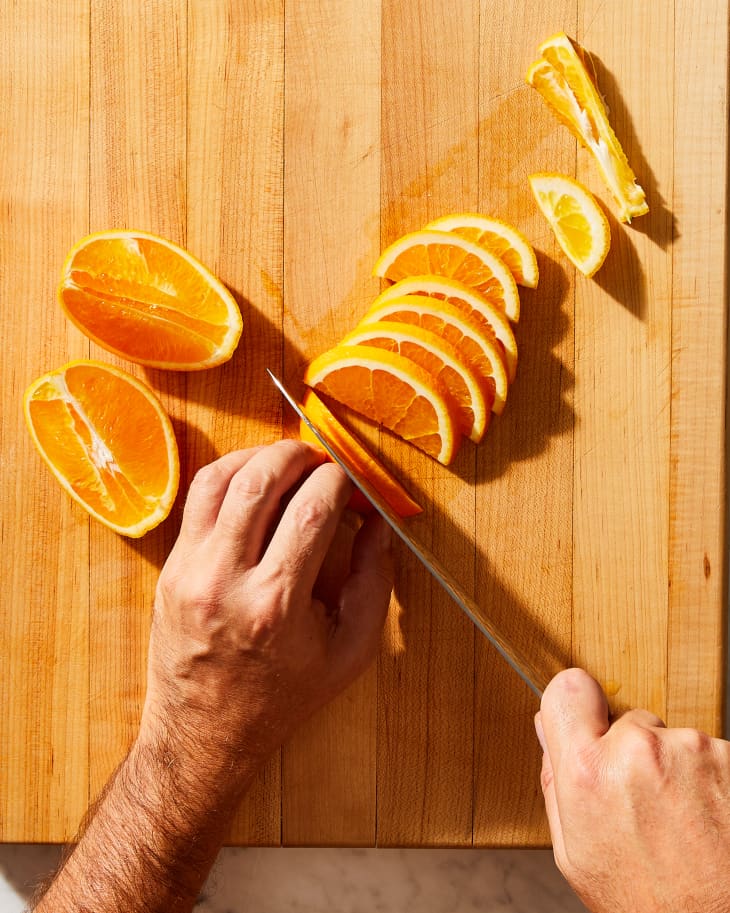 someone slicing oranges into wedges