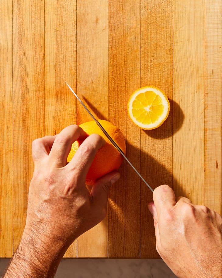 someone cutting the ends off of an orange