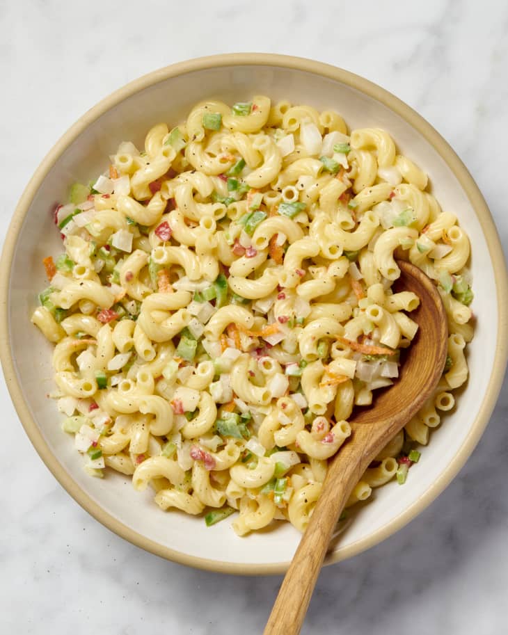 over head shot of macaroni salad with a wooden spoon on marble surface