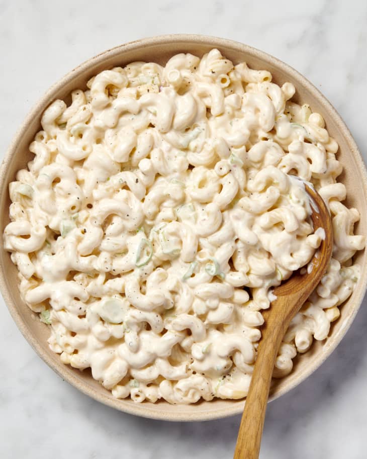 over head shot of macaroni salad with a wooden spoon on marble surface