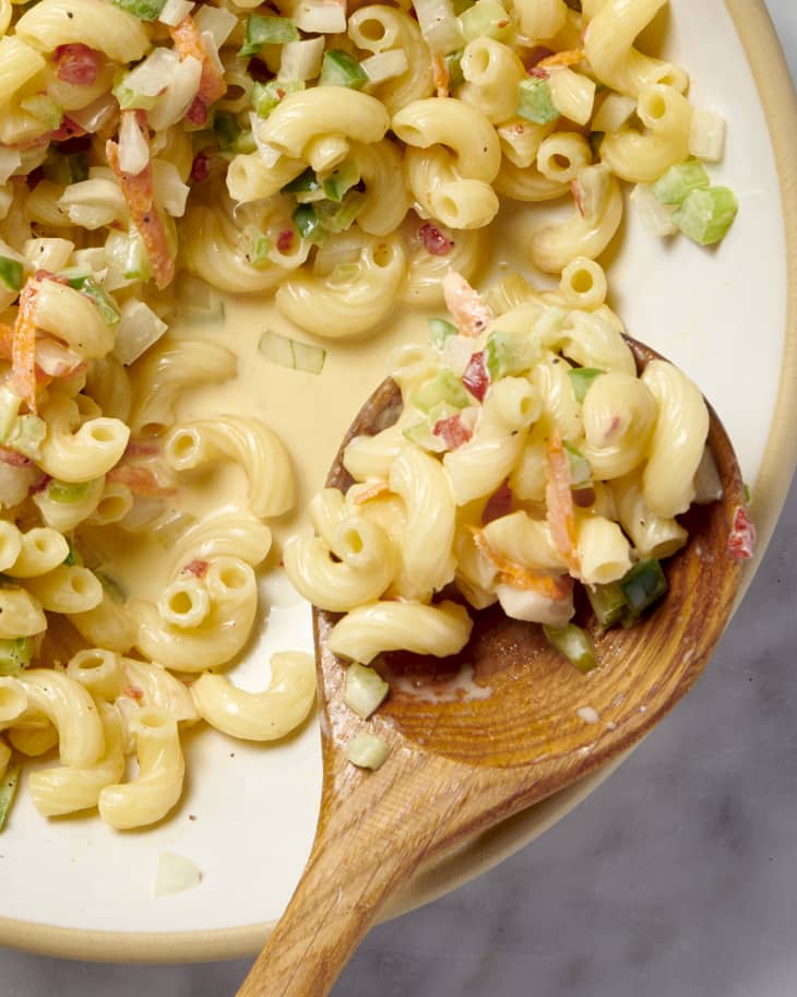 close up shot of macaroni salad with on a wooden spoon