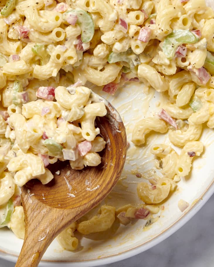 close up shot of macaroni salad with on a wooden spoon