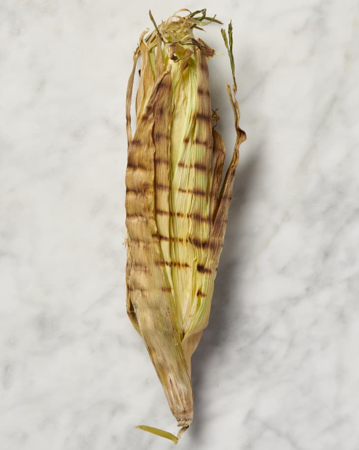 grilled corn in husk on marble