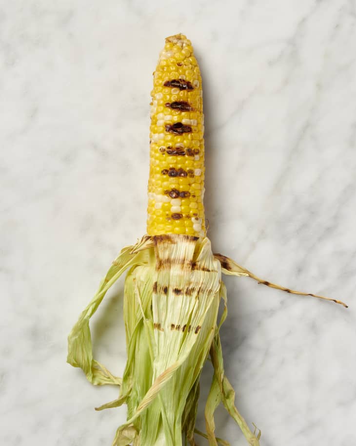 grilled corn in husk without silk on marble