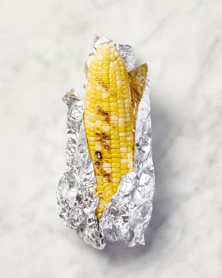 grilled corn in tin foil on marble