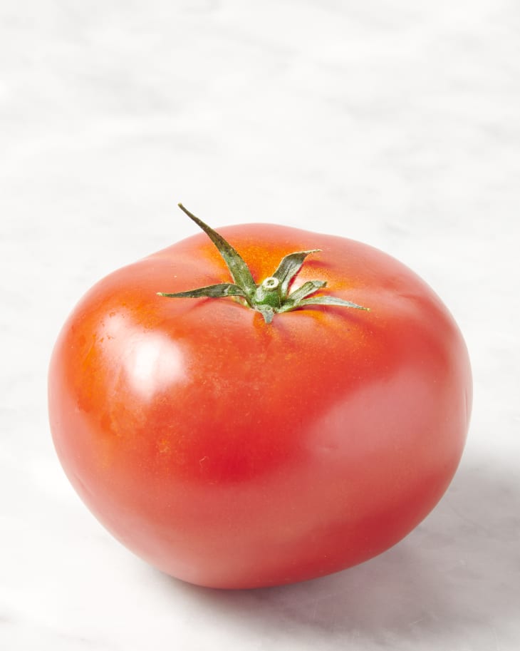 photo of a beefsteak tomato with the stem side up on a marble surface