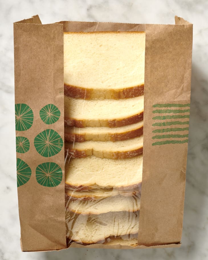 Overhead view of eight slices of bread in a paper bag with a clear plastic layer in the middle.