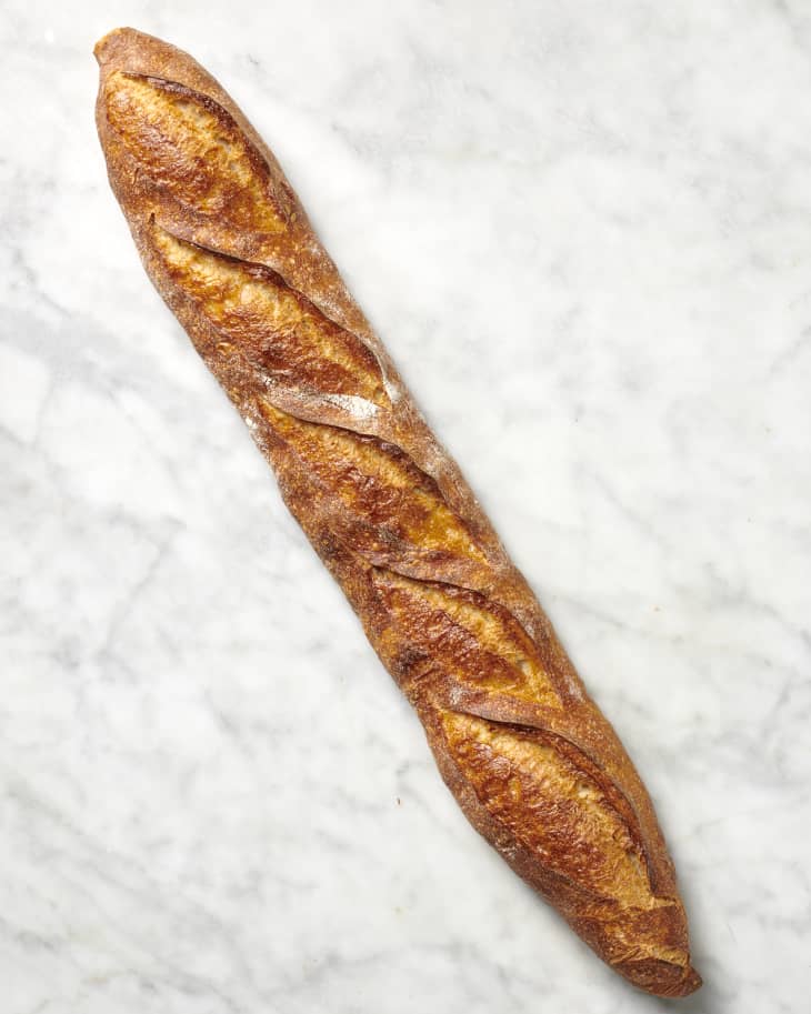 Overhead view of a baguette on a marble surface.