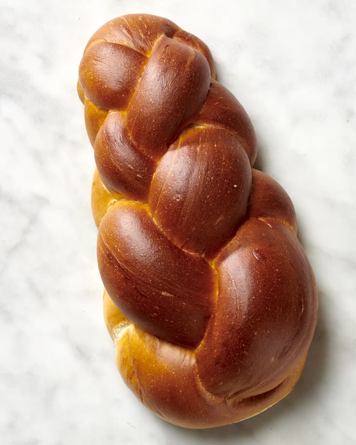 Overhead view of a loaf of challah bread on a marble surface.