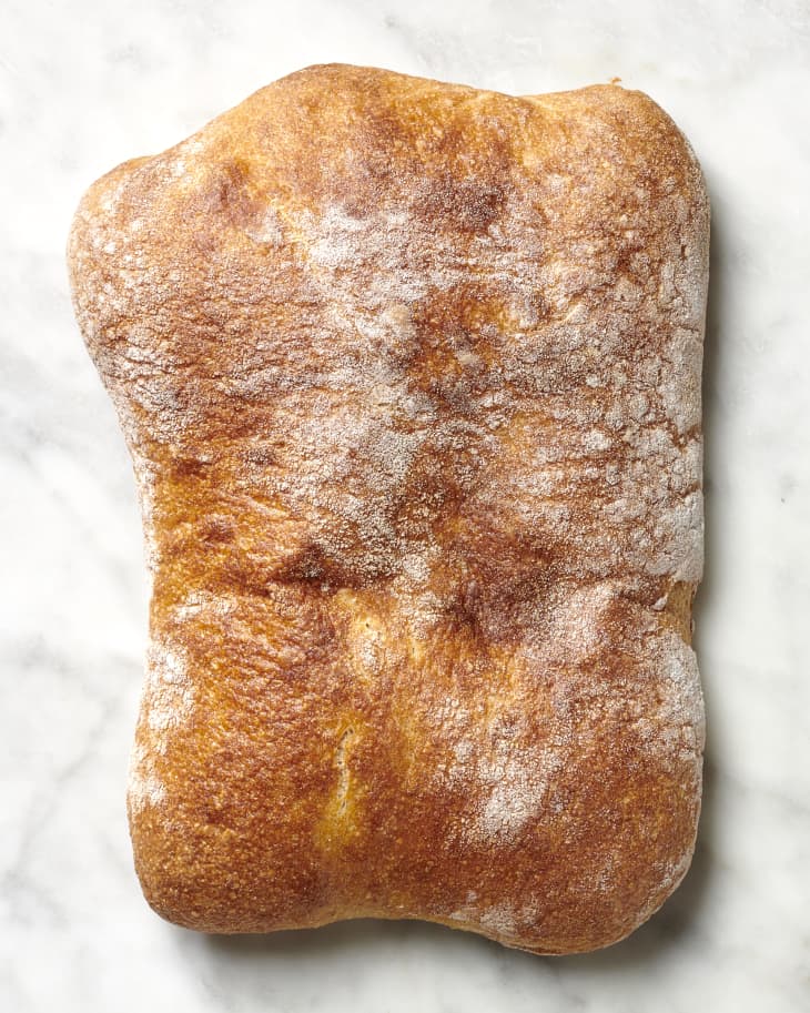 Overhead view of a ciabatta loaf on a marble surface.
