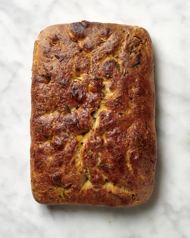 Overhead view of a loaf of focaccia on a marble surface.