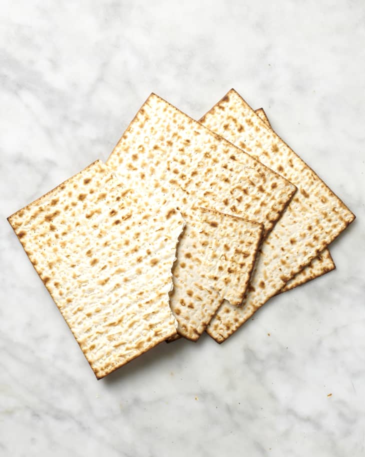 Overhead view of four pieces of matzo, and the top piece is broken apart.