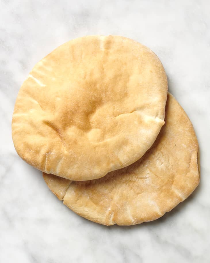 Overhead view of two pieces of pita bread on a marble surface.