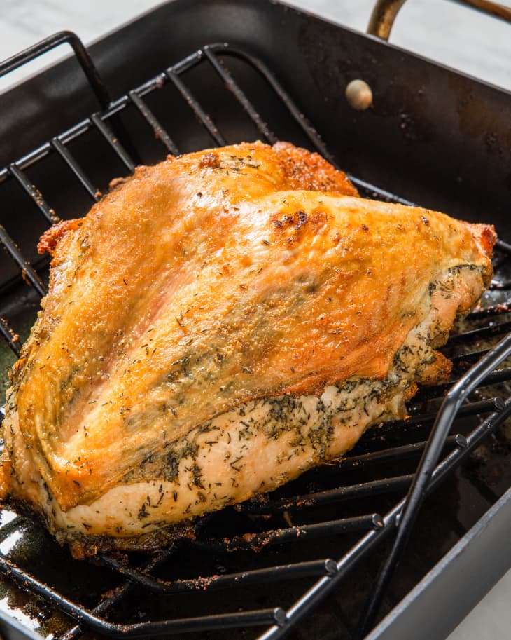 Angled view of a cooked turkey in a black pan.