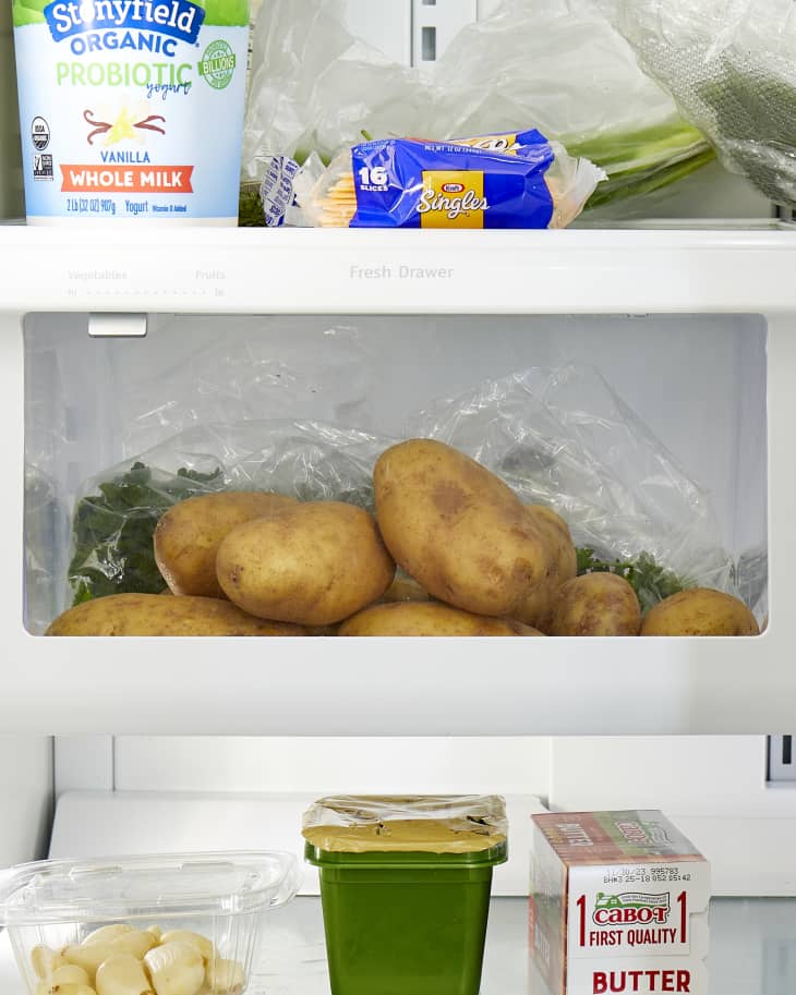 Overhead view of potatoes in the crisper drawer of a fridge.