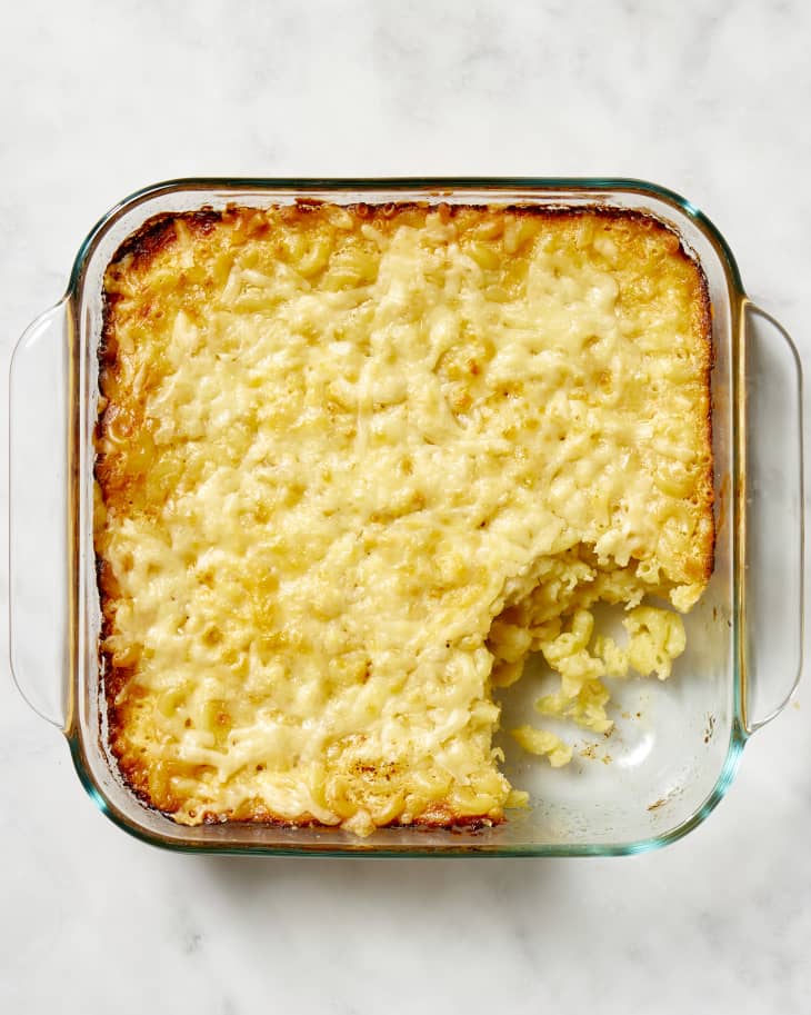 Overhead view of mac and cheese in a square, glass baking dish, with a scoop taken out of the bottom right corner.