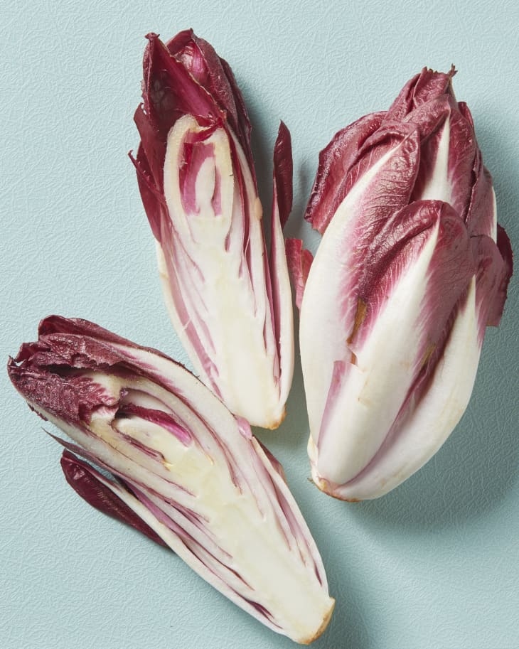 Overhead view of red belgian endives on a a blue cutting board.