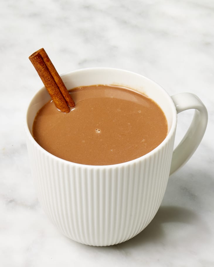 Angled shot of Ina Garten's hot chocolate recipe in a white ribbed mug, with a cinnamon stick resting in the mug.