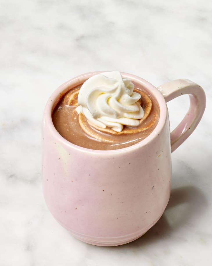Angled shot of Ree Drummond's hot chocolate recipe in a pink mug, topped with whipped cream.