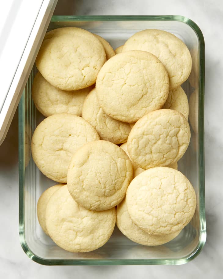 Overhead shot of sugar cookies in a rectangular glass container, stacked.