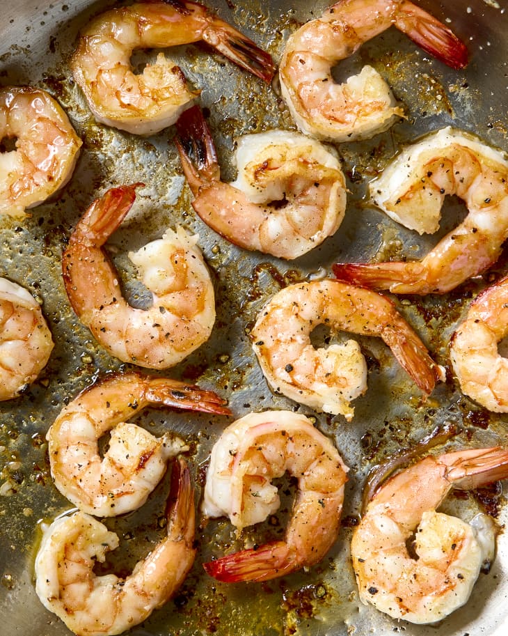 overhead shot of cooked shrimp in a silver frying pan.