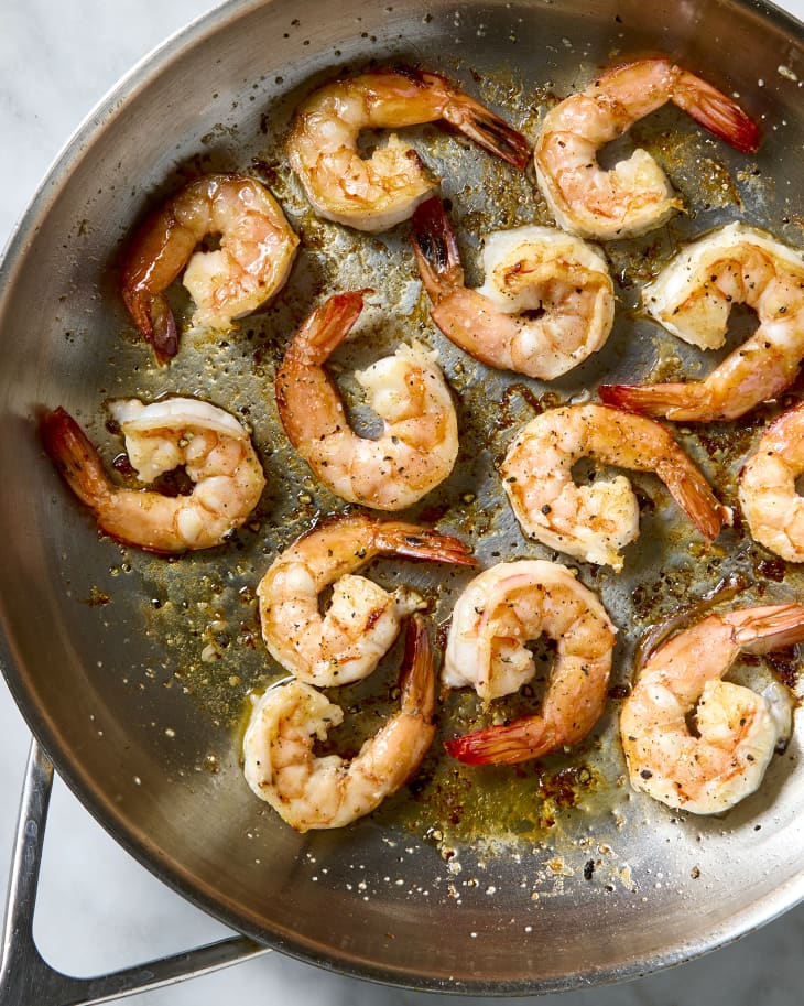 overhead shot of cooked shrimp in a silver frying pan.