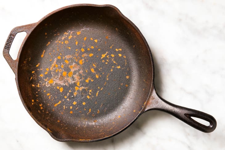 A rusty cast iron skillet on a marble surface
