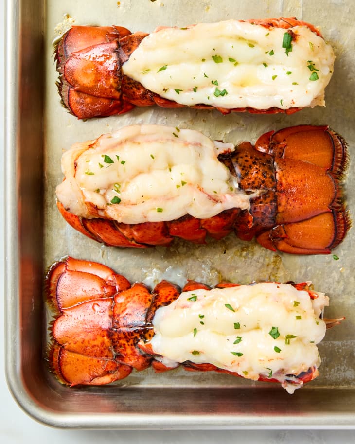 overhead shot of three lobster tails on a baking sheet.