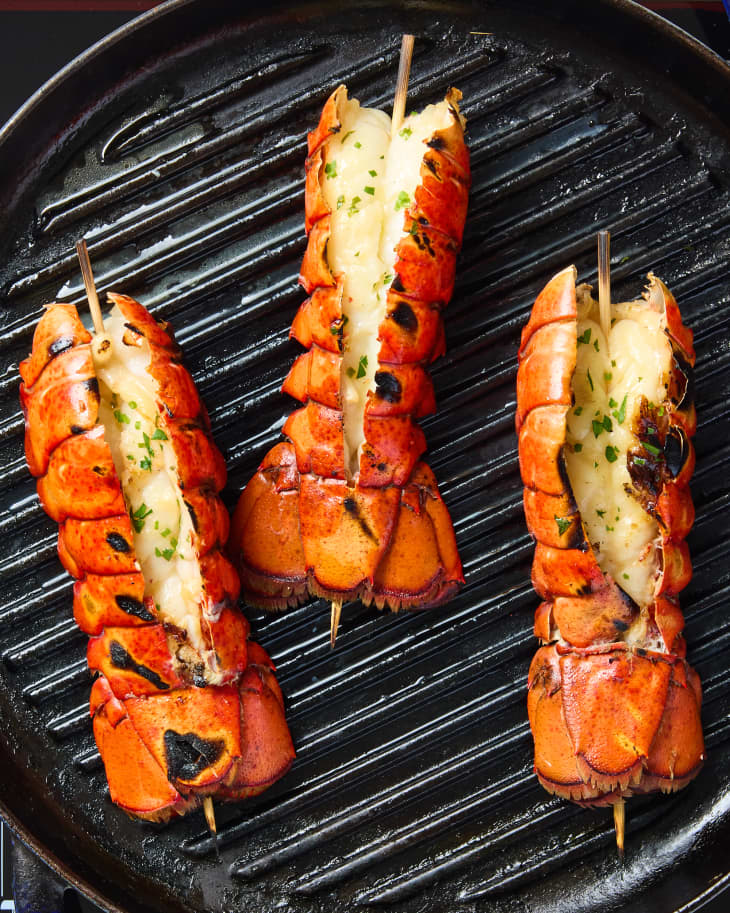 overhead shot of three grilled lobster tails on a grill.