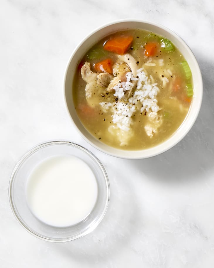 A bowl of chicken and rice soup with a cornstarch slurry next to it.