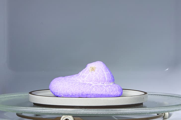 a purple peep on a plate in a microwave.