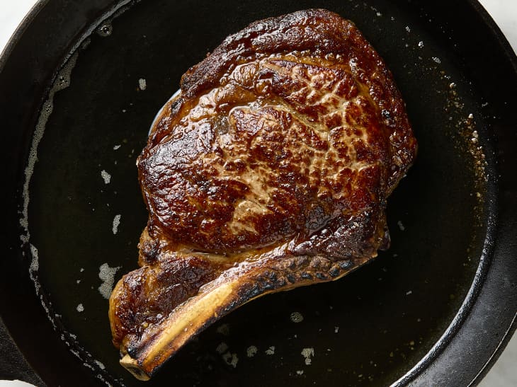 overhead shot of a piece of steak cooking in a cast iron