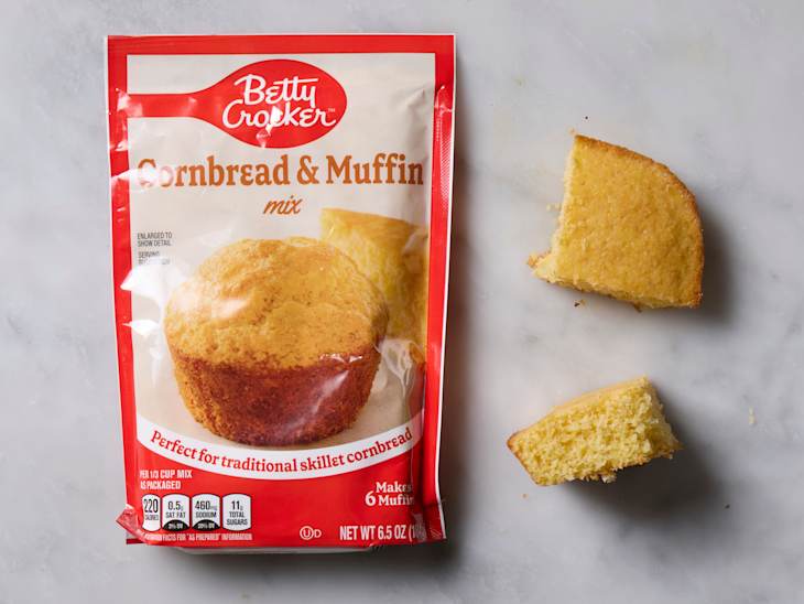 overhead shot of Betty Crocker cornbread and muffin baking mix, with two pieces of corn bread laying next to the bag