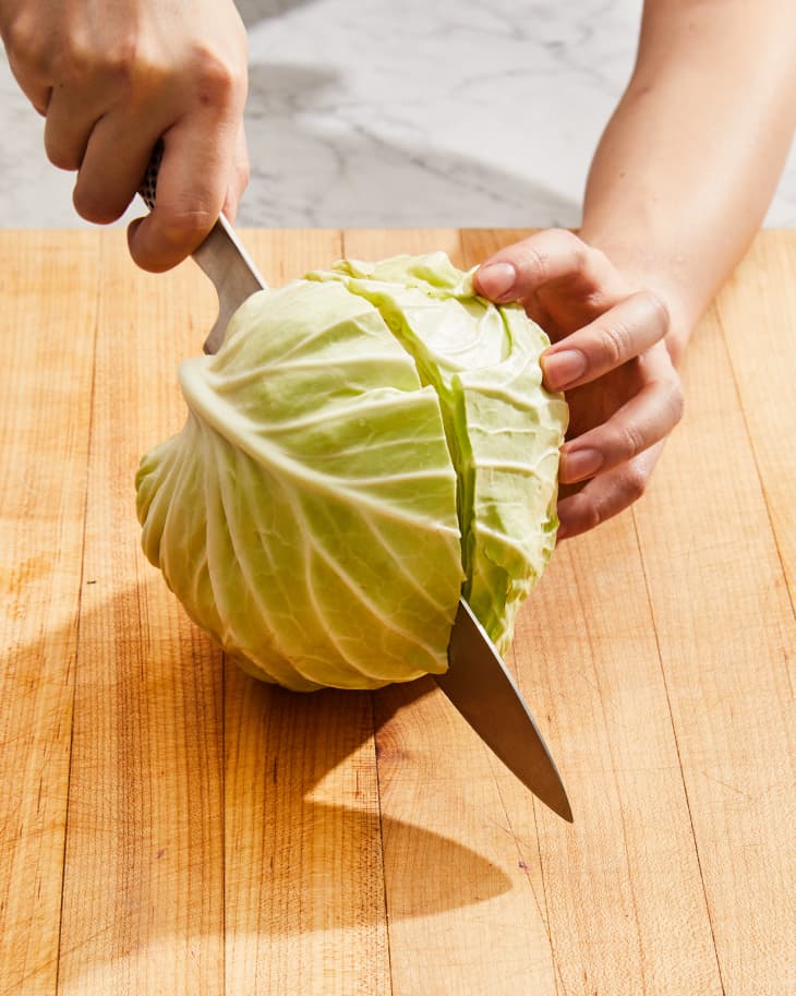 Someone slicing cabbage in half