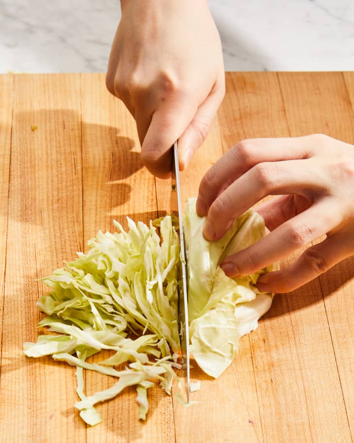someone slicing cabbage with knife.