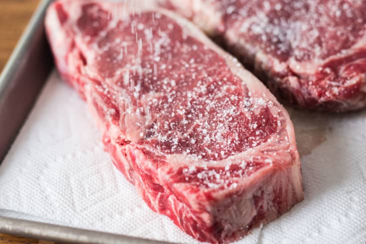 Raw steaks seasoned for cooking on paper towels