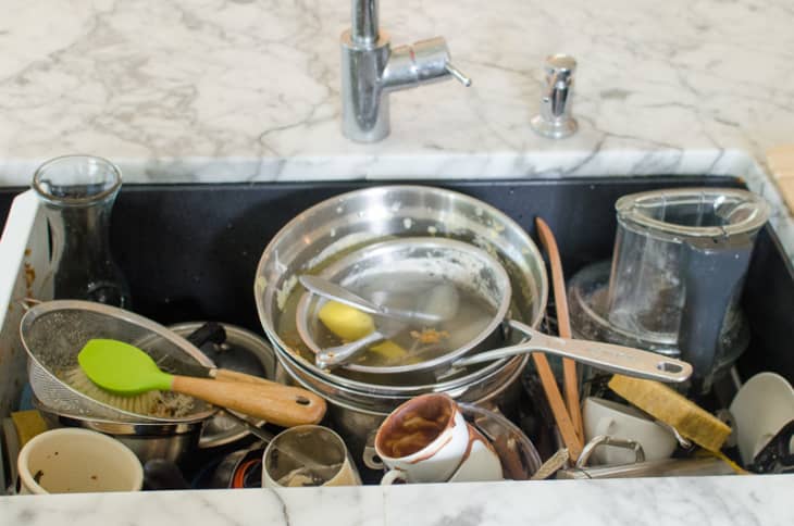 A deep kitchen sink filled with dirty dishes and pans