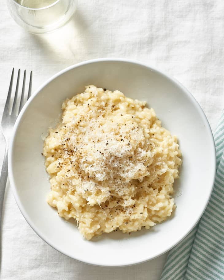A shallow bowl filled with risotto that has been cooked in an Instant Pot, covered with grated parmesan and black pepper